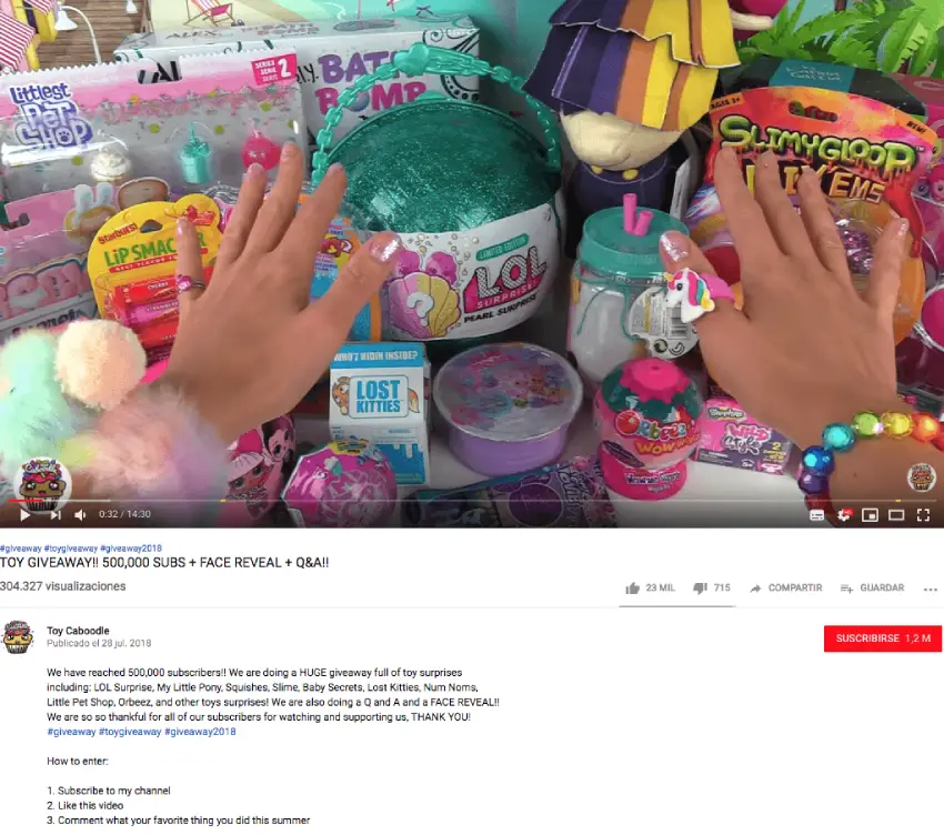 Screenshot of a YouTube video from Toy Caboodle. The image shows a stack of brightly colored toys and the YouTube creator's hands. In the caption, there is a list of giveaway prizes and the giveaway rules.